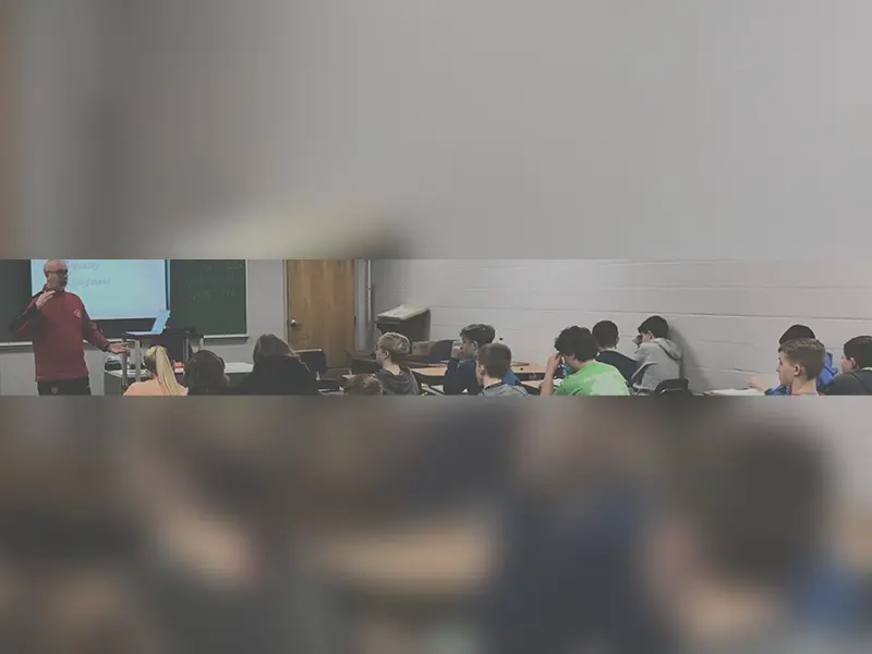 A group of people sitting in front of a projector screen.