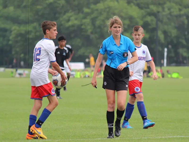 A referee and two young boys playing soccer.