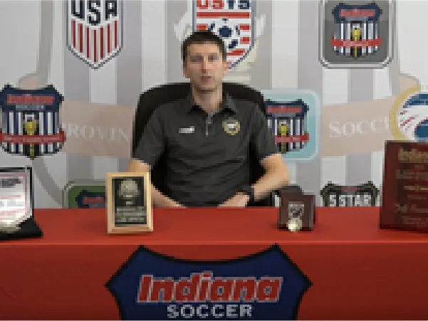 A man sitting at a table with a plaque and trophy.