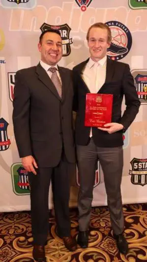 Two men in suits and one is holding a book